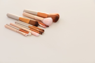 Photo of Different makeup brushes on light background