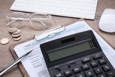 Tax accounting. Calculator, document, pen, coins and keyboard on wooden table, closeup
