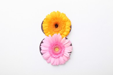Photo of Number 8 shape hole in white paper with beautiful flowers, top view