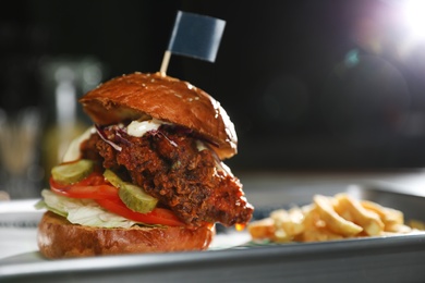 Tray with delicious burger on table against dark background. Space for text