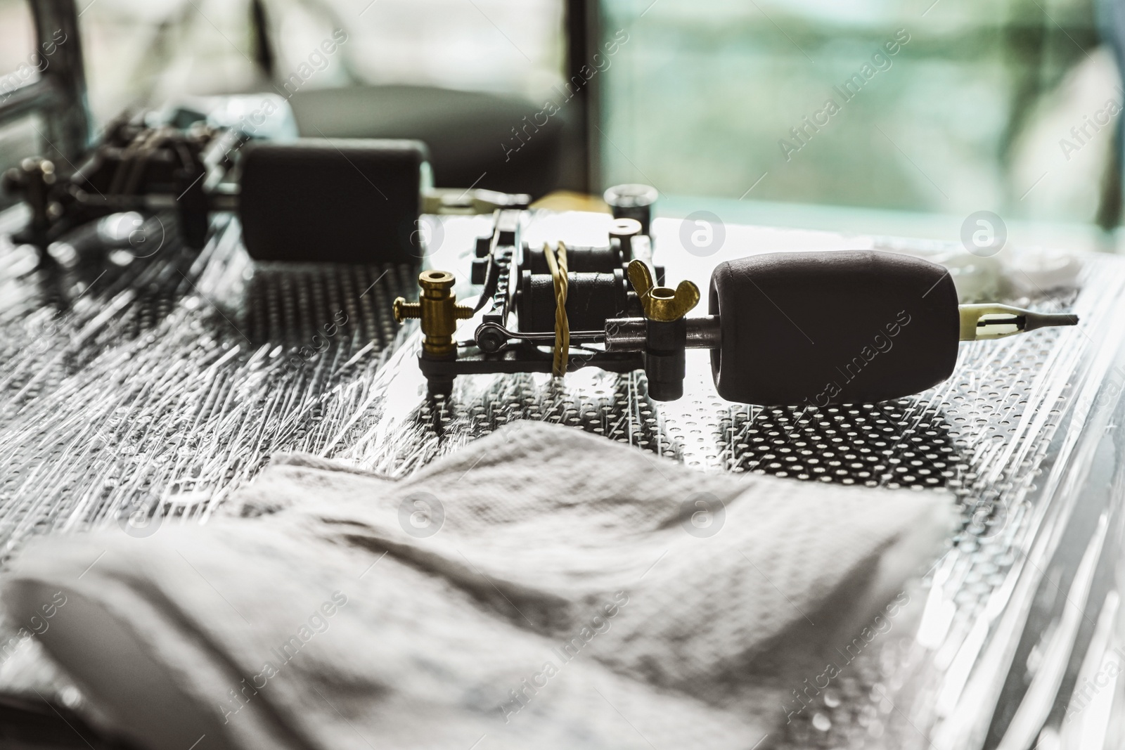 Photo of Modern professional tattoo machine on table in salon