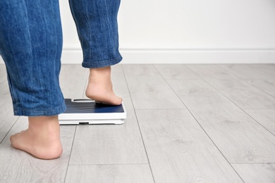 Photo of Overweight woman using scales indoors