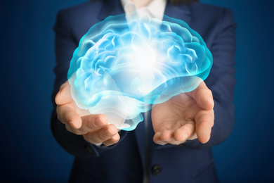 Image of Young woman holding digital image of brain in hands on blue background, closeup
