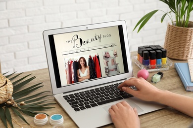 Photo of Woman working with beauty blogger site on laptop at table, closeup