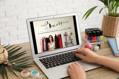 Woman working with beauty blogger site on laptop at table, closeup