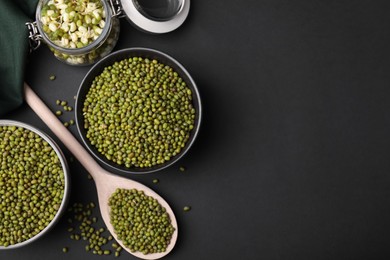 Photo of Different dishware with green mung beans on black background, flat lay. Space for text