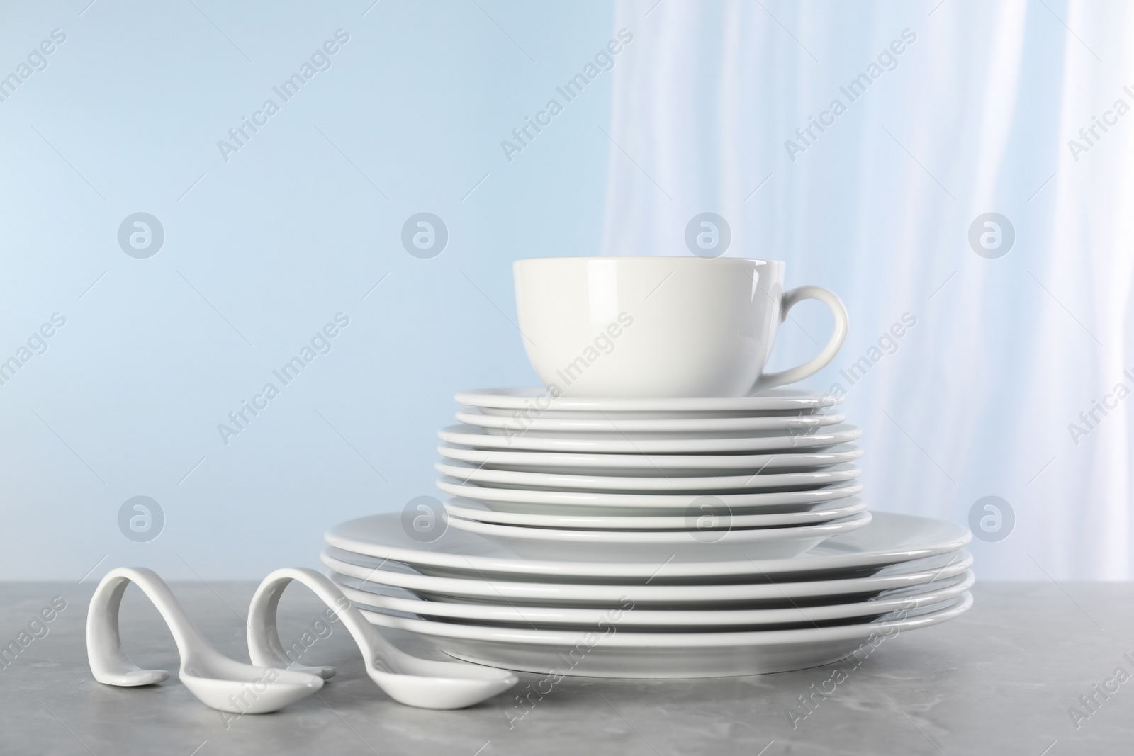 Photo of Set of clean dishware on grey marble table, space for text