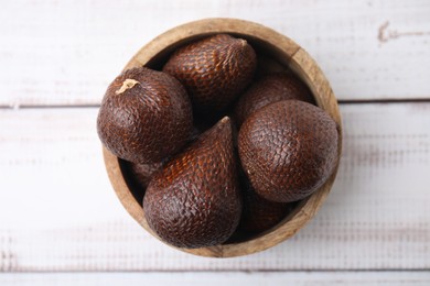 Photo of Fresh salak fruits in bowl on white wooden table, top view