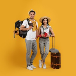 Couple of tourists with tickets, passports and luggage on yellow background