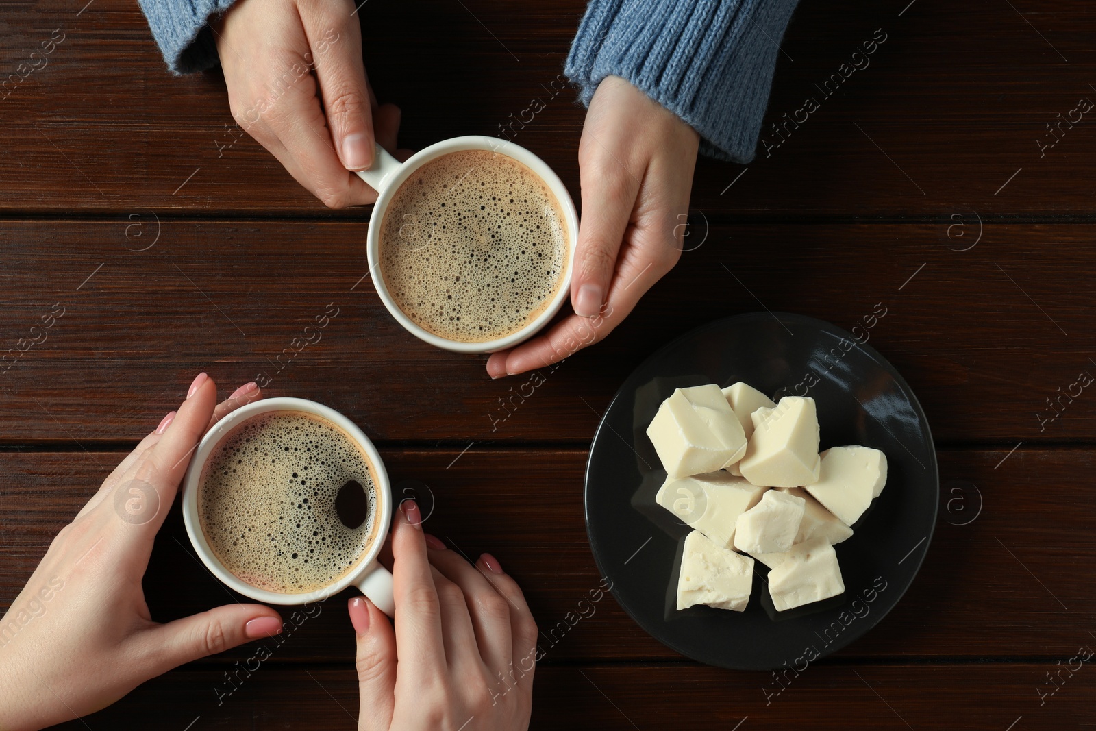 Photo of Women having coffee break at wooden table, top view