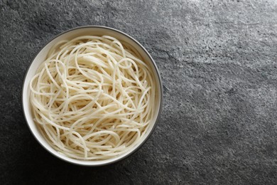 Bowl of tasty cooked rice noodles on grey table, top view. Space for text