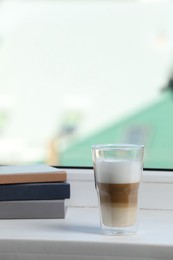 Photo of Books and glass with latte on white window sill