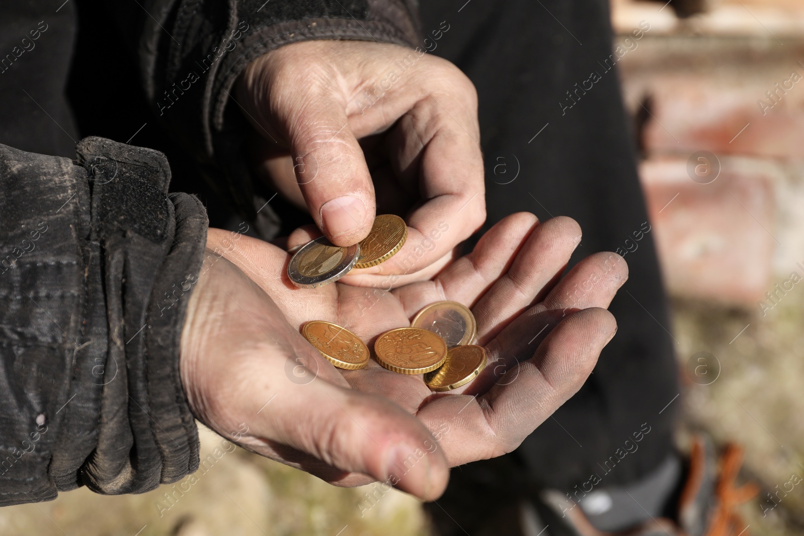 Photo of Poor homeless man holding coins outdoors, closeup