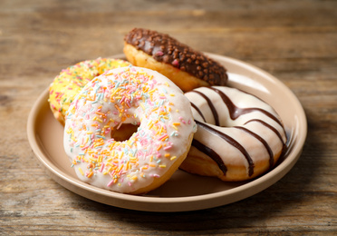 Sweet delicious glazed donuts on wooden table