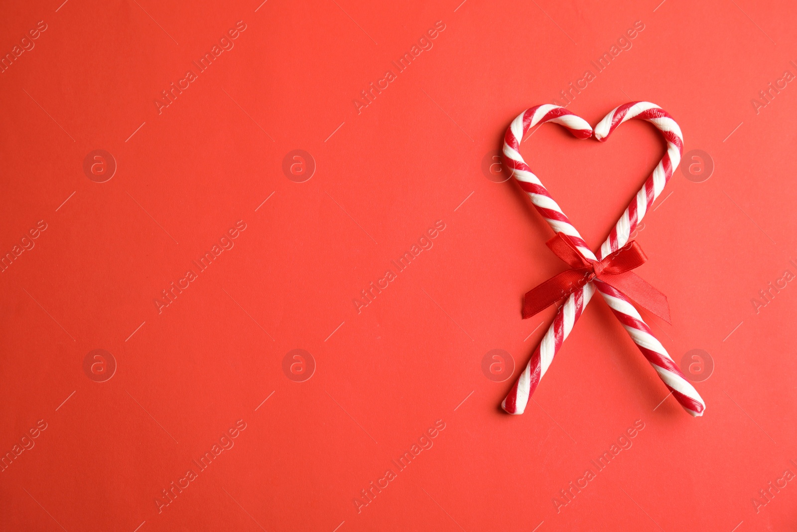 Photo of Candy canes on red background, flat lay. Space for text