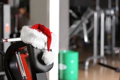 Photo of Santa Claus hat on modern exercise machine in gym