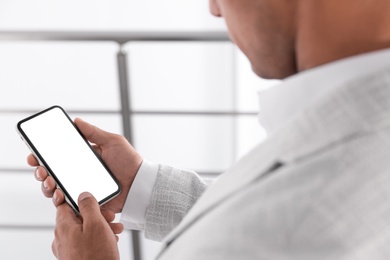 Man using mobile phone with empty screen indoors, closeup