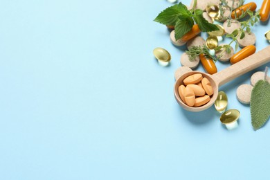 Photo of Different pills and herbs on light blue background, above view with space for text. Dietary supplements