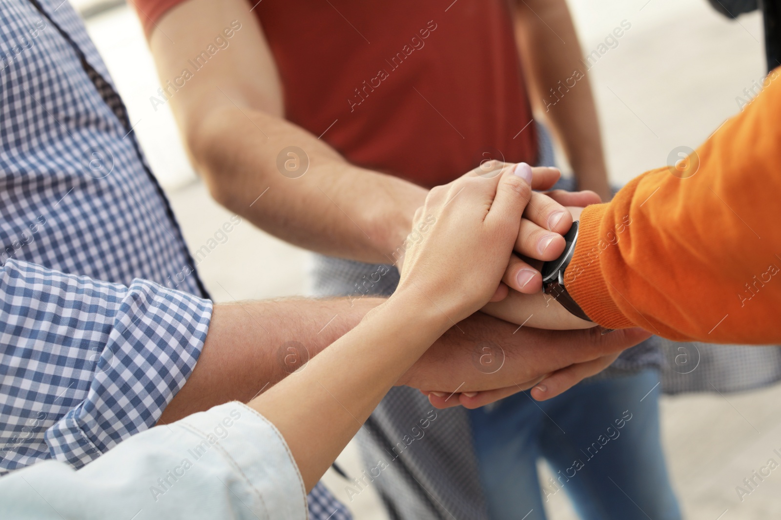 Photo of Group of people holding hands together outdoors, closeup