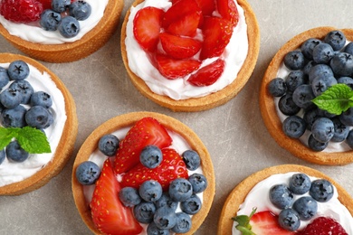 Photo of Delicious sweet pastries with berries on grey table, flat lay