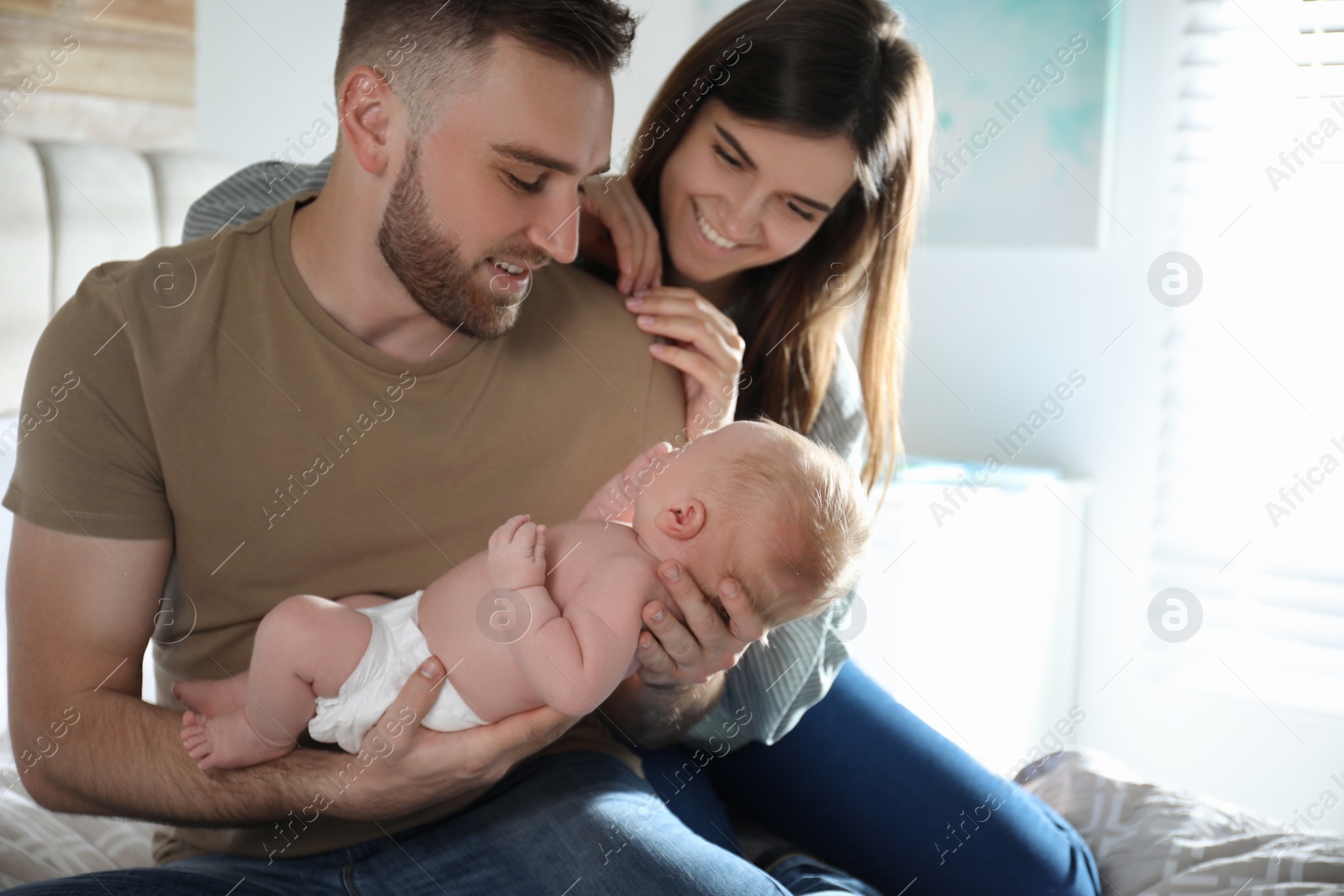 Photo of Happy couple with their newborn baby at home