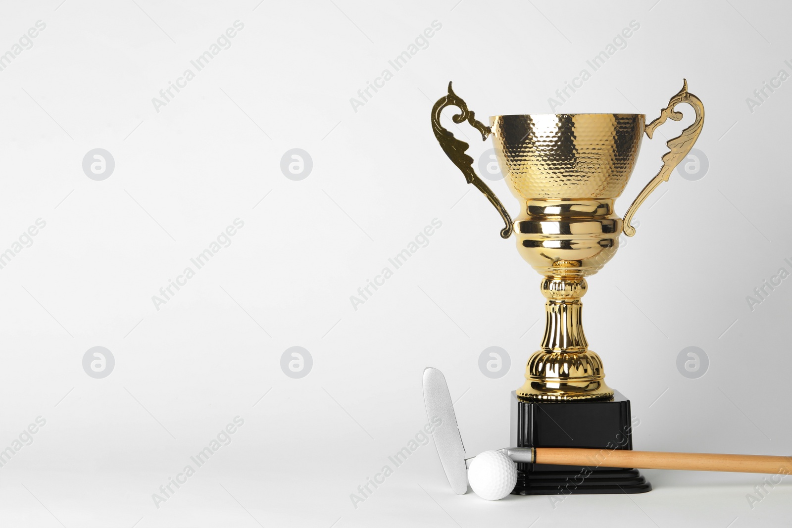 Photo of Golden trophy cup, golf club and ball on white background. Space for text