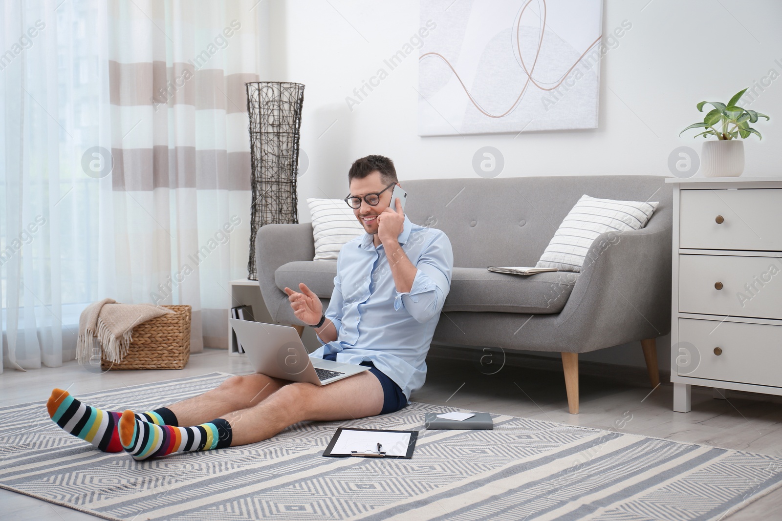 Photo of Businessman in shirt and underwear talking on phone during video call at home