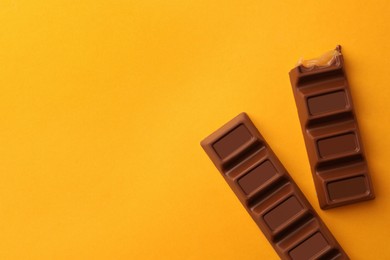 Tasty chocolate bars on yellow background, flat lay. Space for text