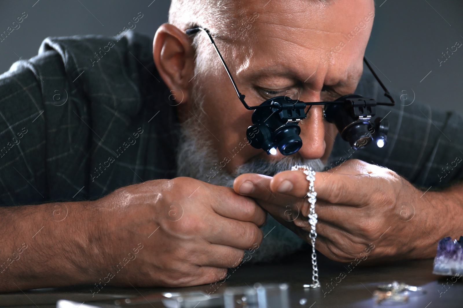 Photo of Male jeweler evaluating diamond bracelet in workshop, closeup view