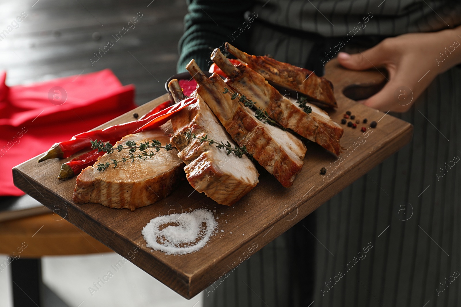 Photo of Woman holding serving board with delicious roasted ribs, closeup