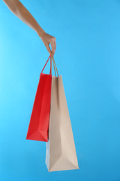 Photo of Woman with paper shopping bags on light blue background, closeup