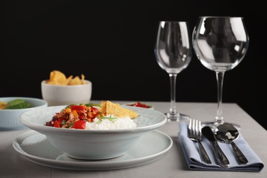 Photo of Tasty chili con carne served with rice on gray table. Dinner in restaurant