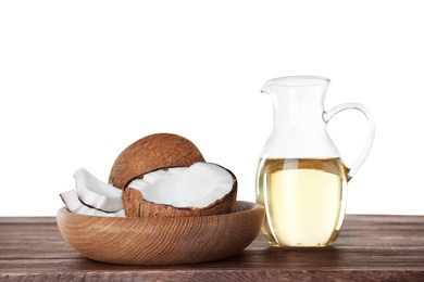 Photo of Composition with natural organic oil and ripe coconuts on wooden table against white background