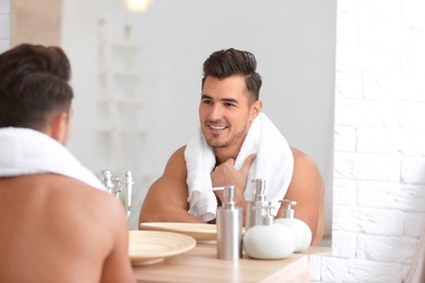 Young man with stubble ready for shaving near mirror in bathroom