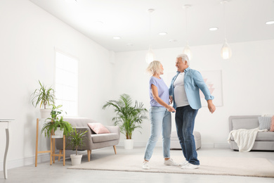 Happy mature couple dancing together in living room
