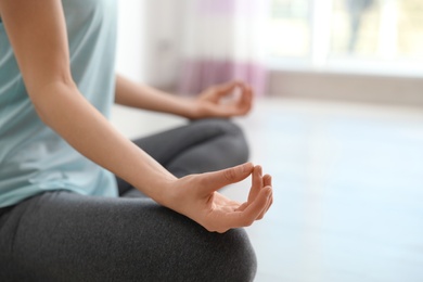 Photo of Young woman meditating indoors, closeup with space for text. Zen concept