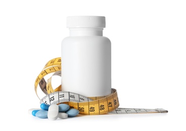 Weight loss pills and bottle with measuring tape on white background