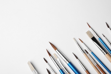 Photo of Different paint brushes on white background, top view. Space for text