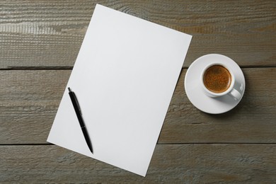 Photo of Blank paper sheet, pen and cup of coffee on wooden table, flat lay. Space for text