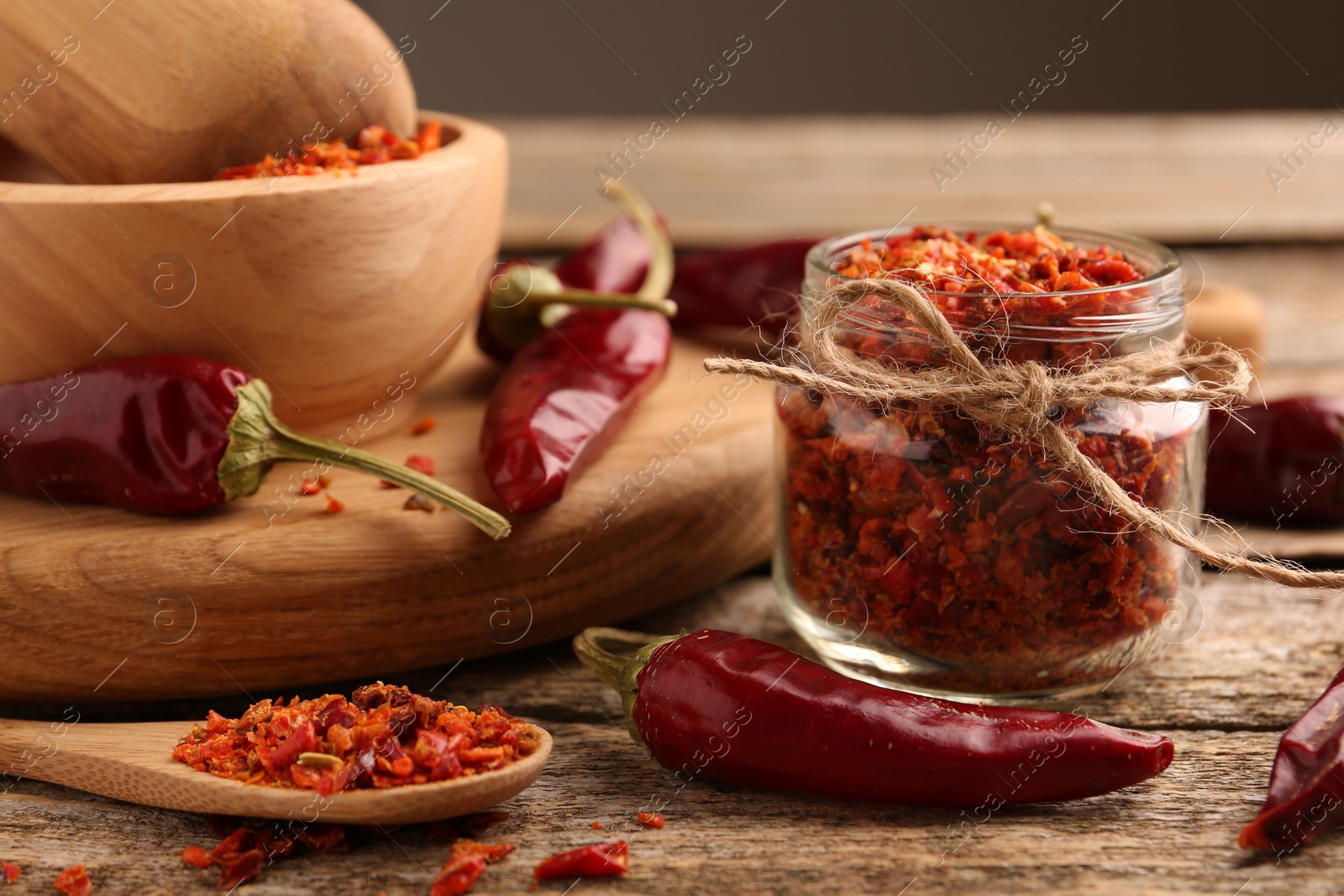 Photo of Chili pepper flakes and pods on wooden table, closeup