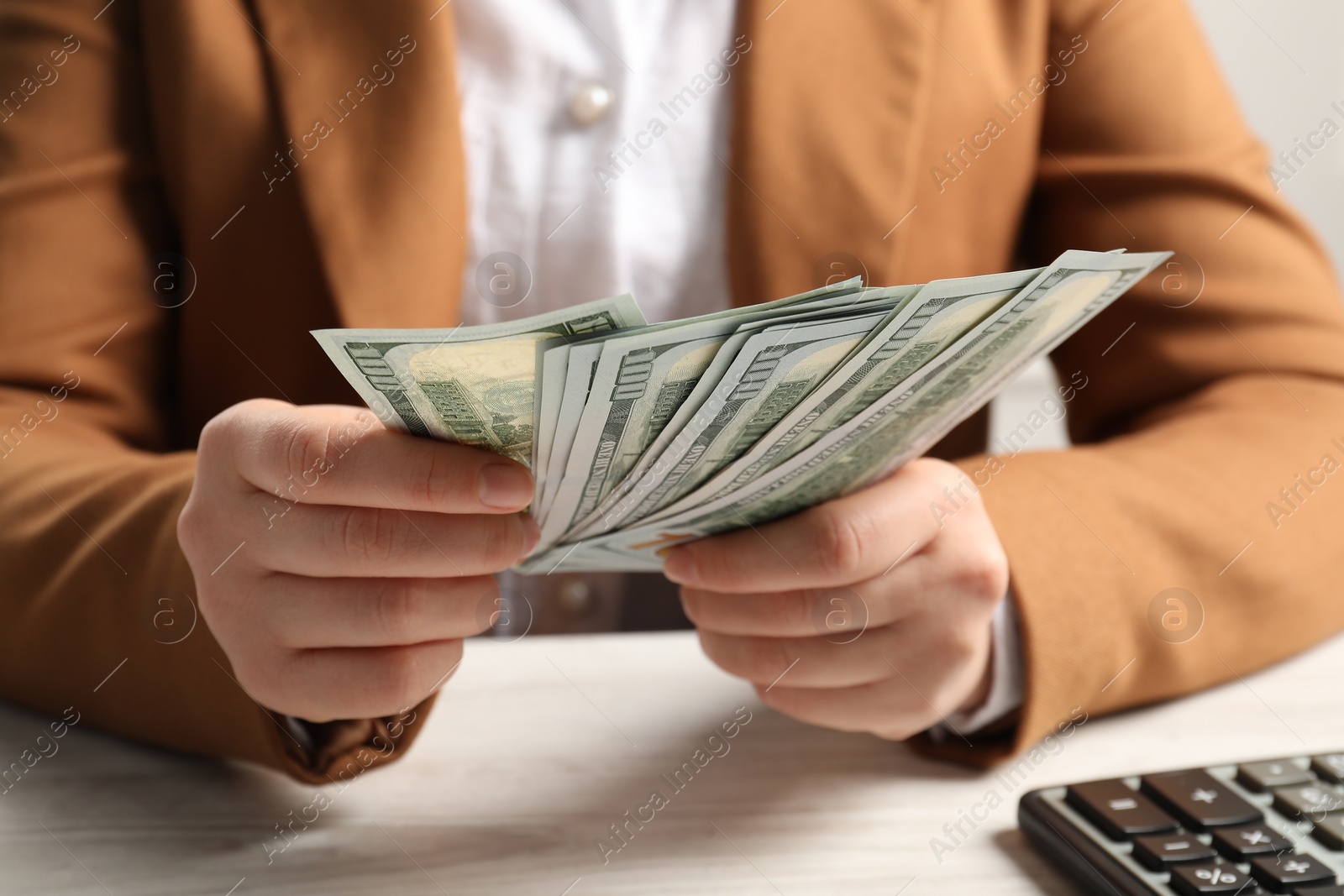 Photo of Money exchange. Woman holding dollar banknotes at white wooden table, closeup