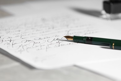 Photo of Elegant fountain pen and handwritten letter on table, closeup