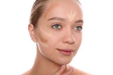 Young woman with different shades of skin foundation on her face against white background