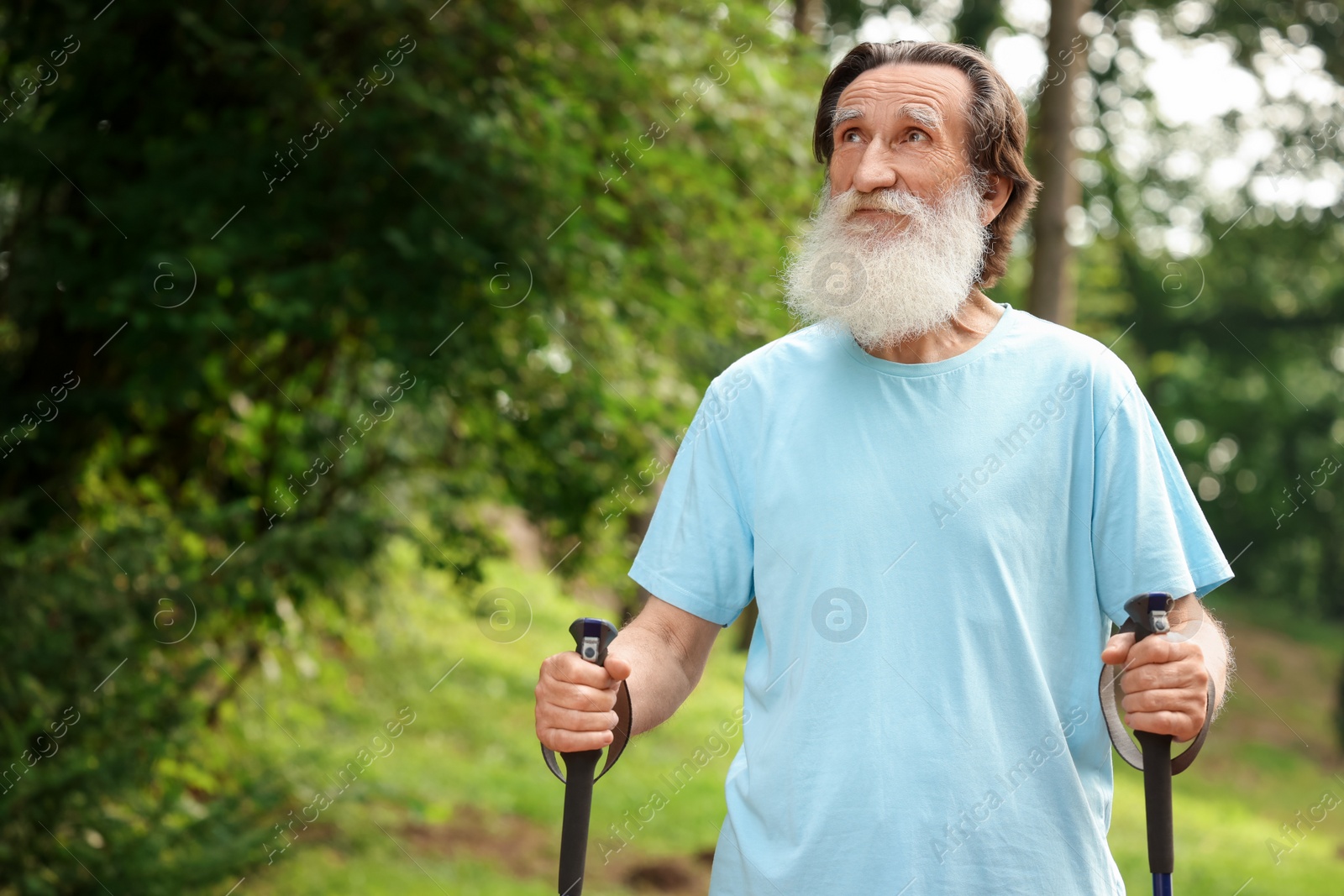 Photo of Senior man with Nordic walking poles outdoors, space for text