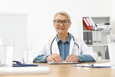 Photo of Professional doctor sitting at wooden table in clinic