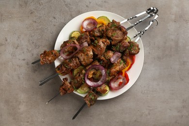 Metal skewers with delicious meat and vegetables served on grey table, top view