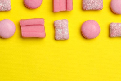 Photo of Pink bubble gums on yellow background, flat lay. Space for text