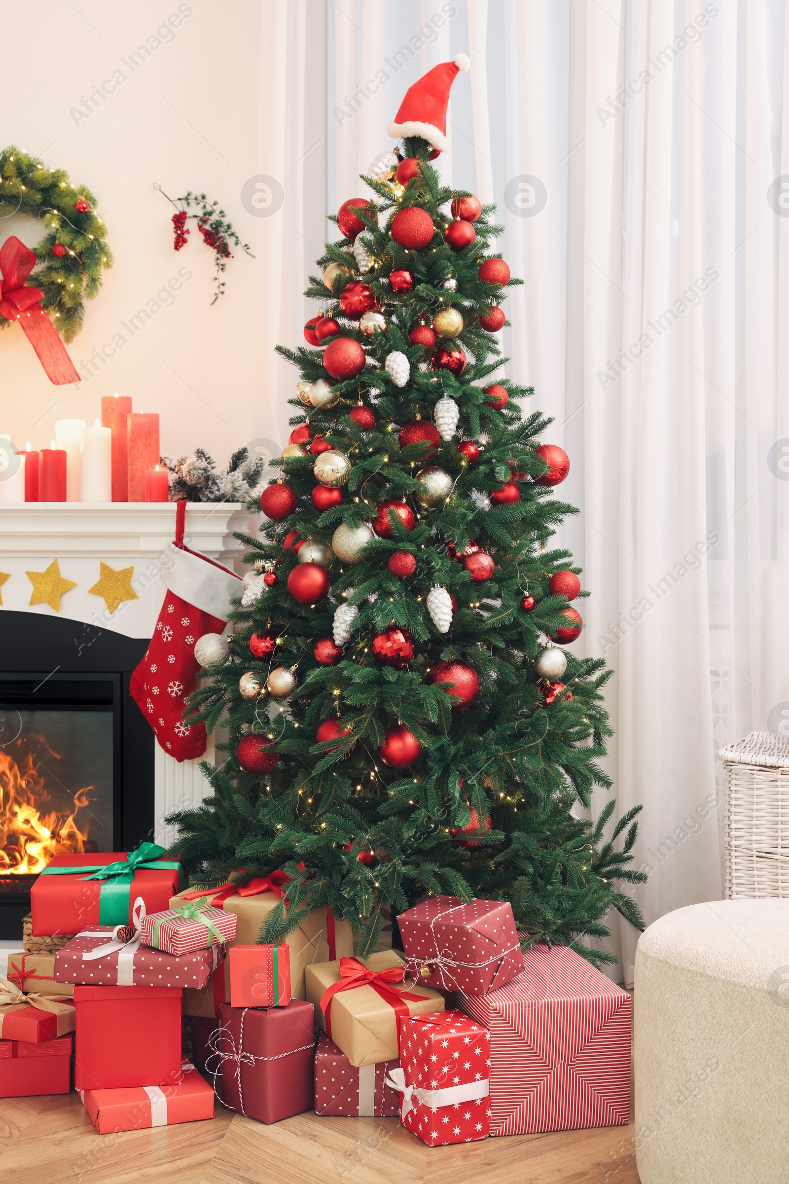 Photo of Beautiful Christmas tree and gift boxes near decorated fireplace in room