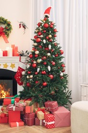 Photo of Beautiful Christmas tree and gift boxes near decorated fireplace in room