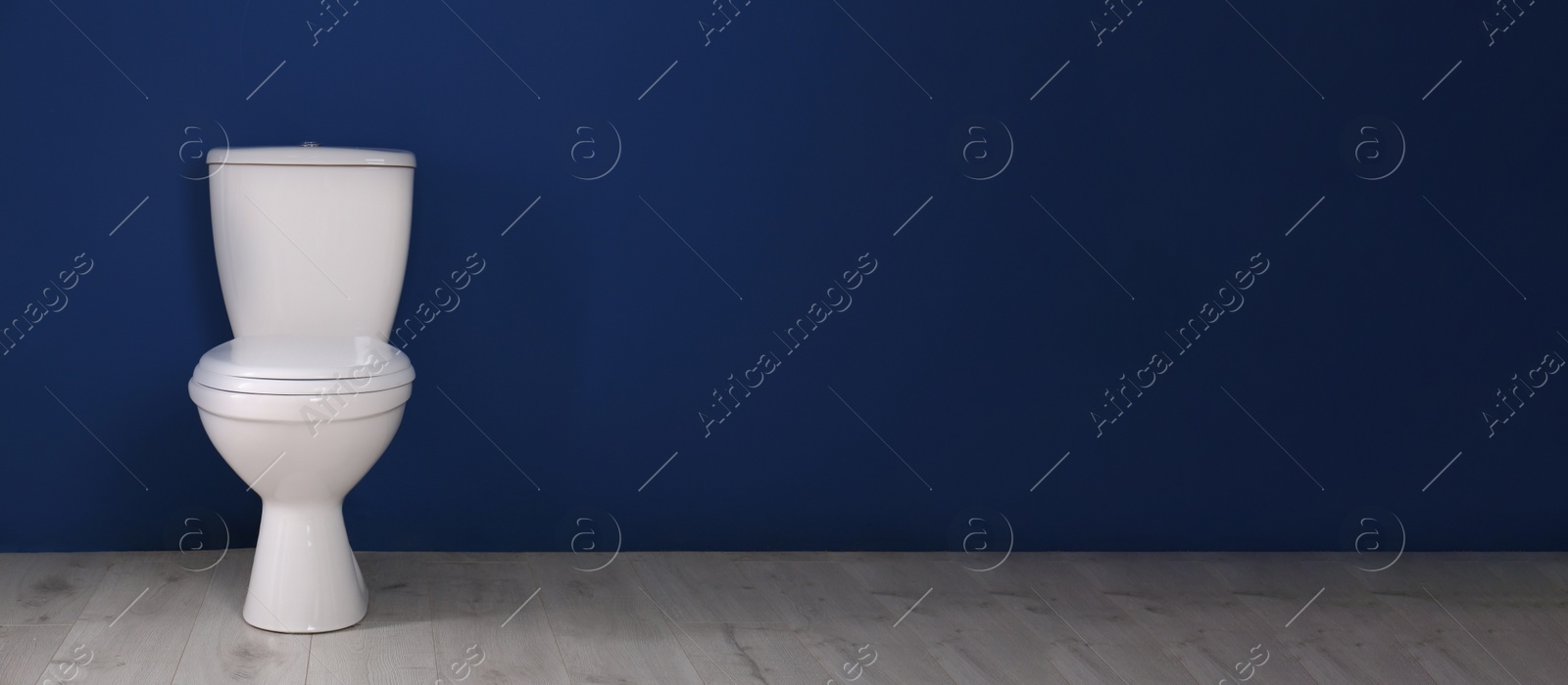 Image of New toilet bowl near blue wall indoors, space for text. Banner design